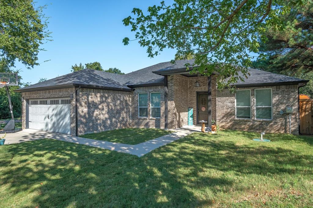 Single story home featuring a front yard, an attached garage, brick siding, and roof with shingles