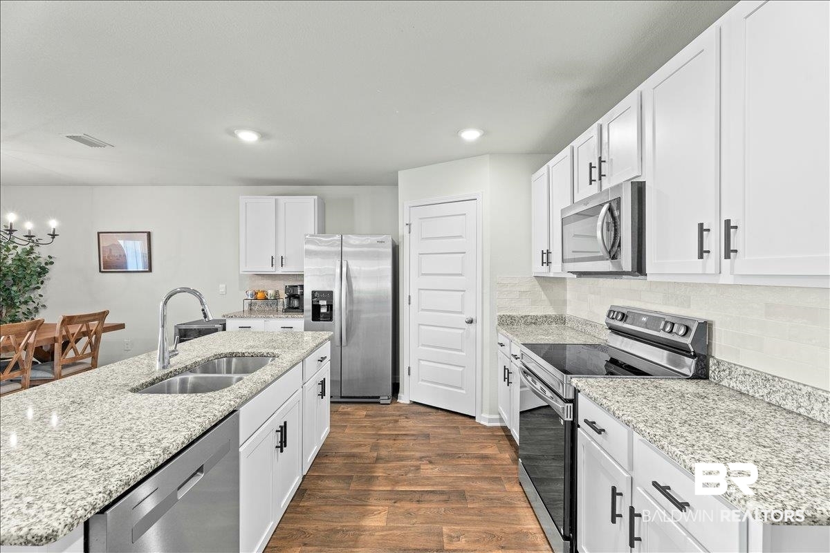 23641 Unbridled Loop Daphne, AL 36526 - Photo 8 of 40 Modern kitchen featuring white cabinetry, granite countertops, and stainless steel appliances including a refrigerator, dishwasher, and microwave
