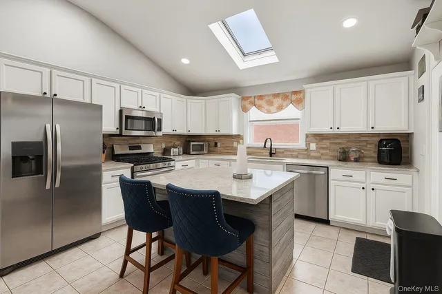 a kitchen with stainless steel appliances granite countertop a sink a stove a refrigerator cabinets and chairs