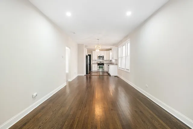 a view of an empty room with wooden floor and window
