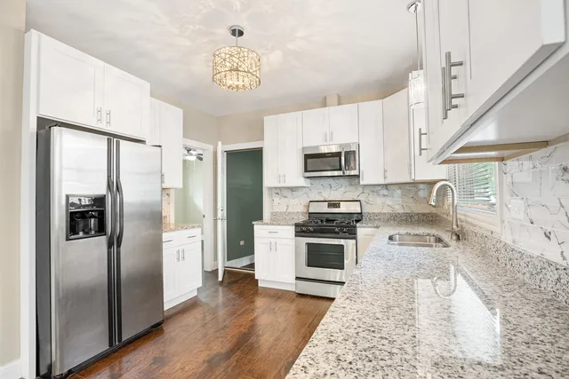 a kitchen with granite countertop white cabinets and white appliances