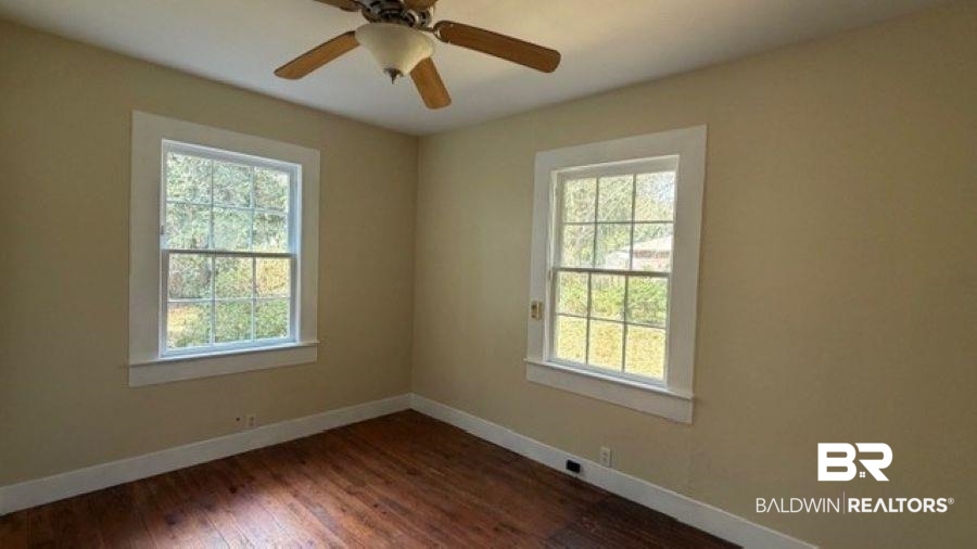 Unfurnished room featuring dark wood-type flooring and a ceiling fan
