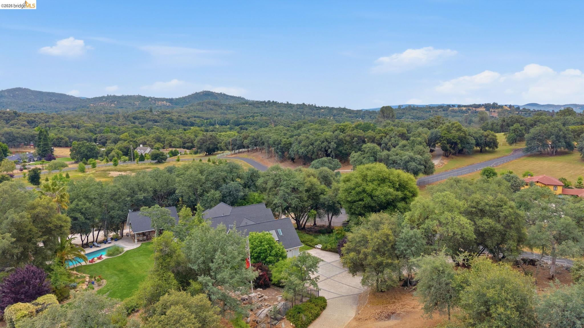 18450 Lambert Lake Road Sonora, CA 95370 - Photo 87 of 87 Expansive property with a dark-pitched roof, large swimming pool, and concrete driveway, surrounded by mature trees and rolling hills