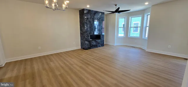 a view of an empty room with wooden floor and windows