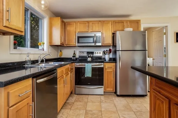 a kitchen with granite countertop a refrigerator stove and sink