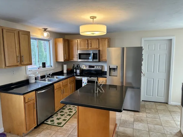a kitchen with stainless steel appliances granite countertop a stove a refrigerator a sink a microwave and a refrigerator
