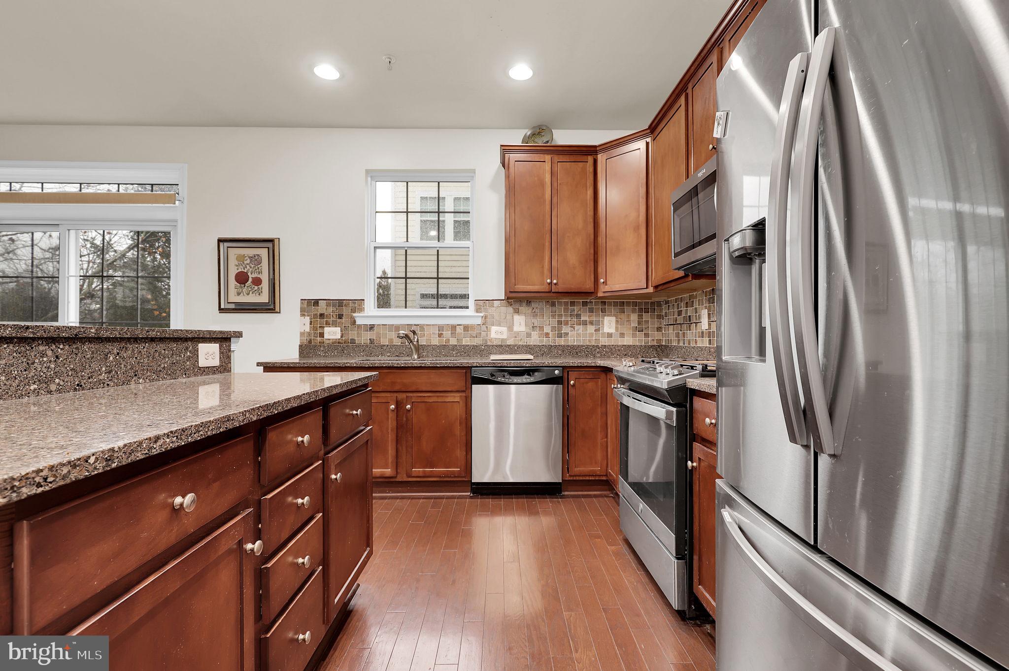 5846 Donovan Lane Ellicott City, MD 21043 - Photo 8 of 31 a kitchen with stainless steel appliances granite countertop a refrigerator a sink dishwasher a stove and white countertops with wooden floor