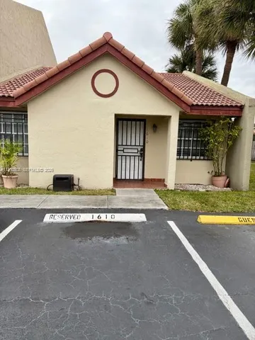a front view of a house with a garden and parking