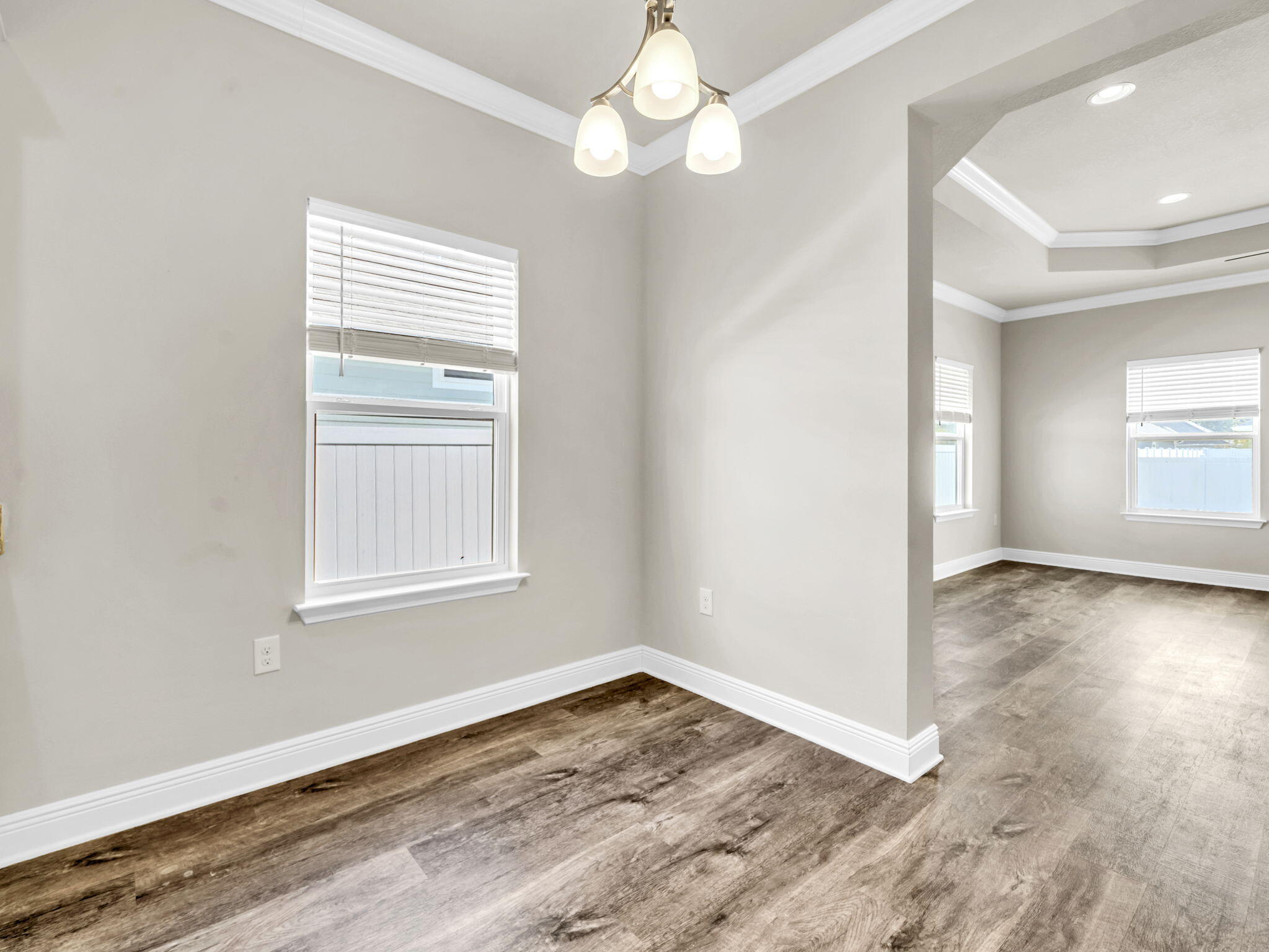 218 Stonegate Drive Santa Rosa Beach, FL 32459 - Photo 16 of 37 an empty room with wooden floor chandelier fan and windows