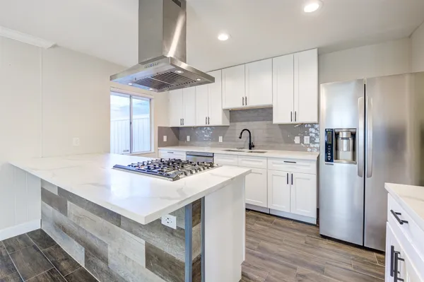 a kitchen with stainless steel appliances white cabinets a sink a stove a refrigerator and island