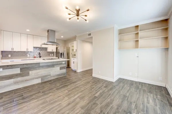 a large kitchen with stainless steel appliances a large window a wooden floor and a sink