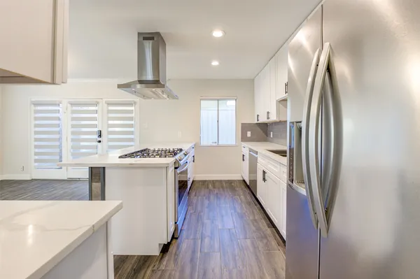 a kitchen with kitchen island granite countertop a sink a counter top space stainless steel appliances and cabinets