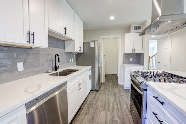 a kitchen with stainless steel appliances a sink dishwasher stove refrigerator and cabinets with wooden floor