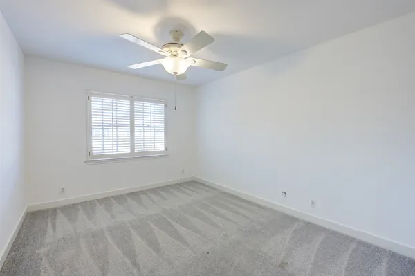 a view of an empty room with a chandelier fan