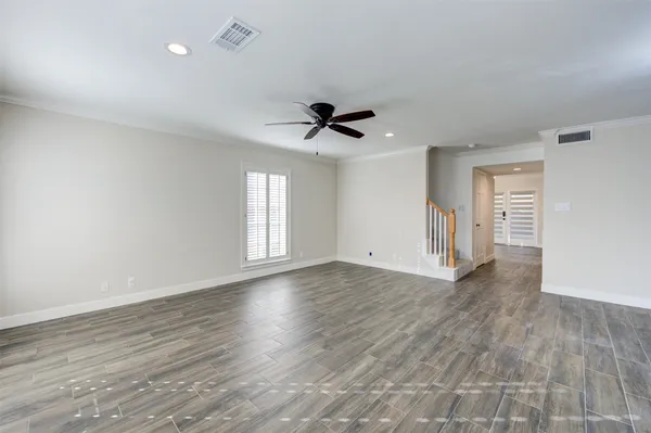 an empty room with wooden floor and ceiling fan