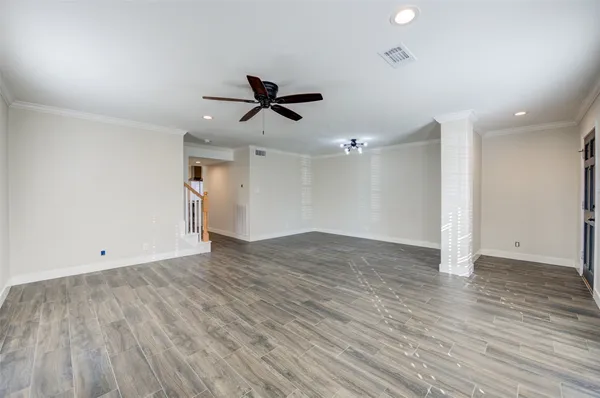 a view of empty room with wooden floor and ceiling fan