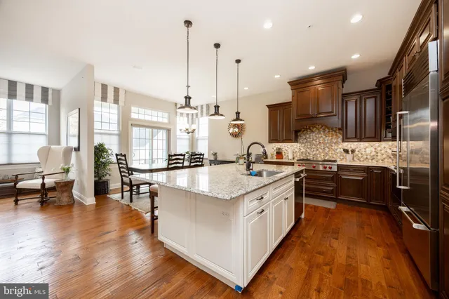 a large kitchen with stainless steel appliances kitchen island granite countertop a large center island a stove a sink a refrigerator and a center island