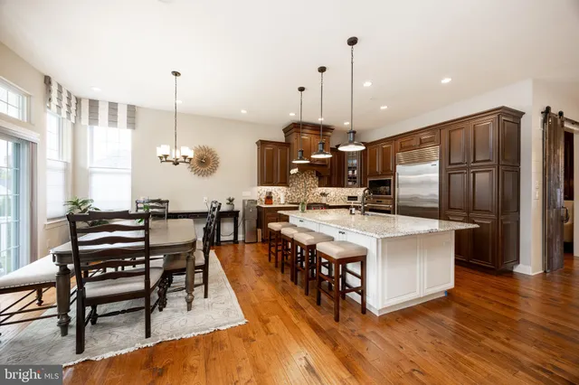 a kitchen with stainless steel appliances kitchen island granite countertop a table chairs and a wooden floor