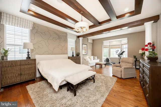 a spacious bedroom with a bed a chandelier and dresser