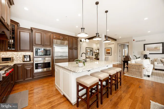 a kitchen with stainless steel appliances granite countertop a stove top oven a sink dishwasher a dining table and chairs with wooden floor