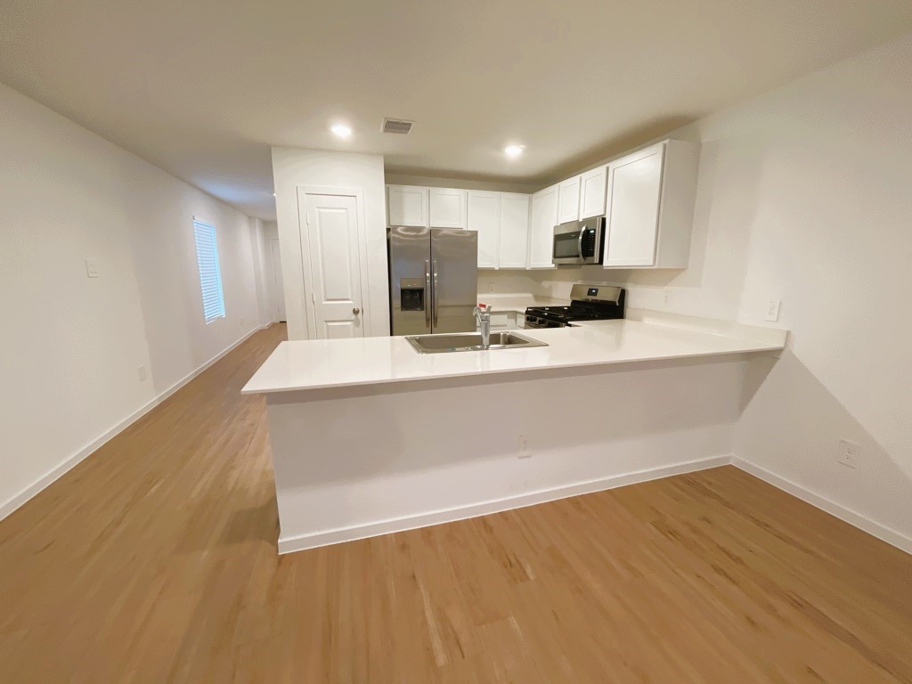 1612 Colina Creek Conroe, TX 77301 - Photo 17 of 33 a large white kitchen with kitchen island a sink dishwasher a stove with wooden floor