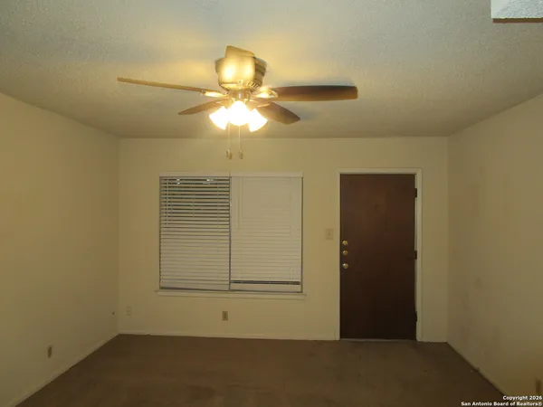 an empty room with windows and fan