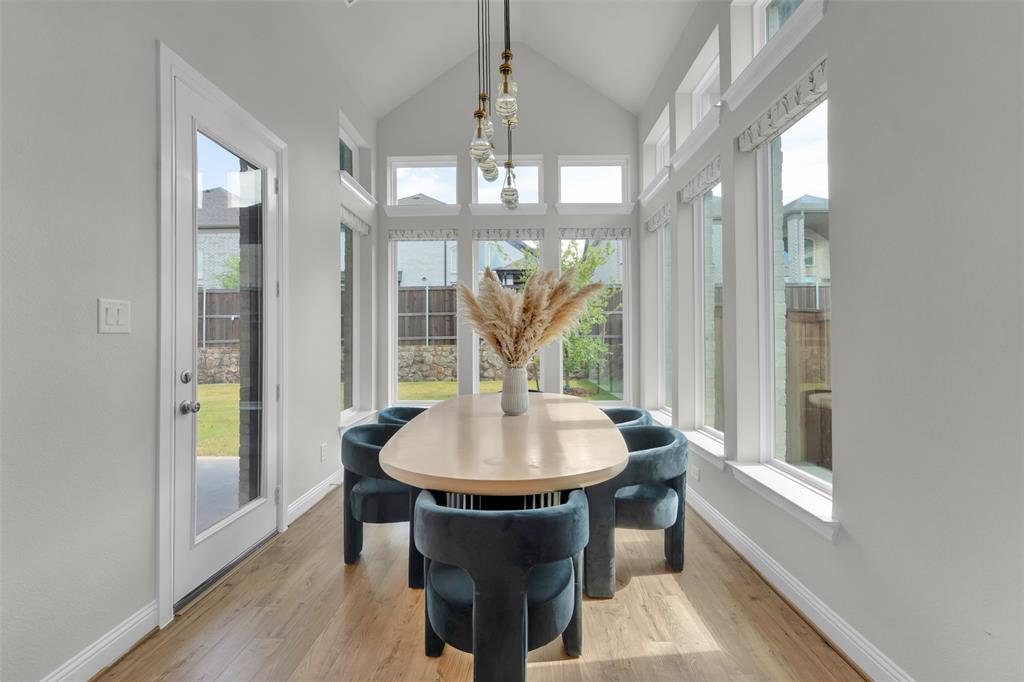 3520 Helios Lane Corinth, TX 76208 - Photo 13 of 37 Sun-filled dining area featuring vaulted ceilings, wood-finish flooring, a full-lite glass door, and extensive window walls