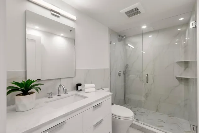 a bathroom with a sink a toilet a large mirror and shower