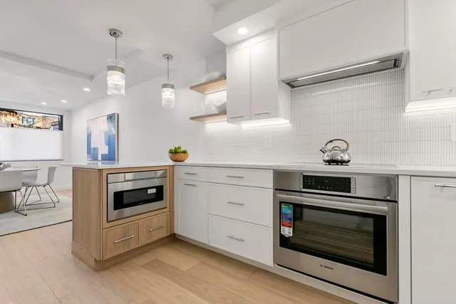 a kitchen with white cabinets stainless steel appliances and wooden floor