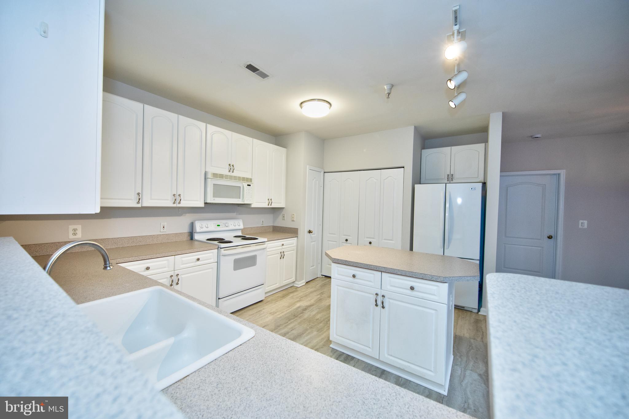 400 Symphony Circle, Unit 74B Cockeysville, MD 21030 - Photo 11 of 36 a kitchen with granite countertop a sink stove and white cabinets with wooden floor