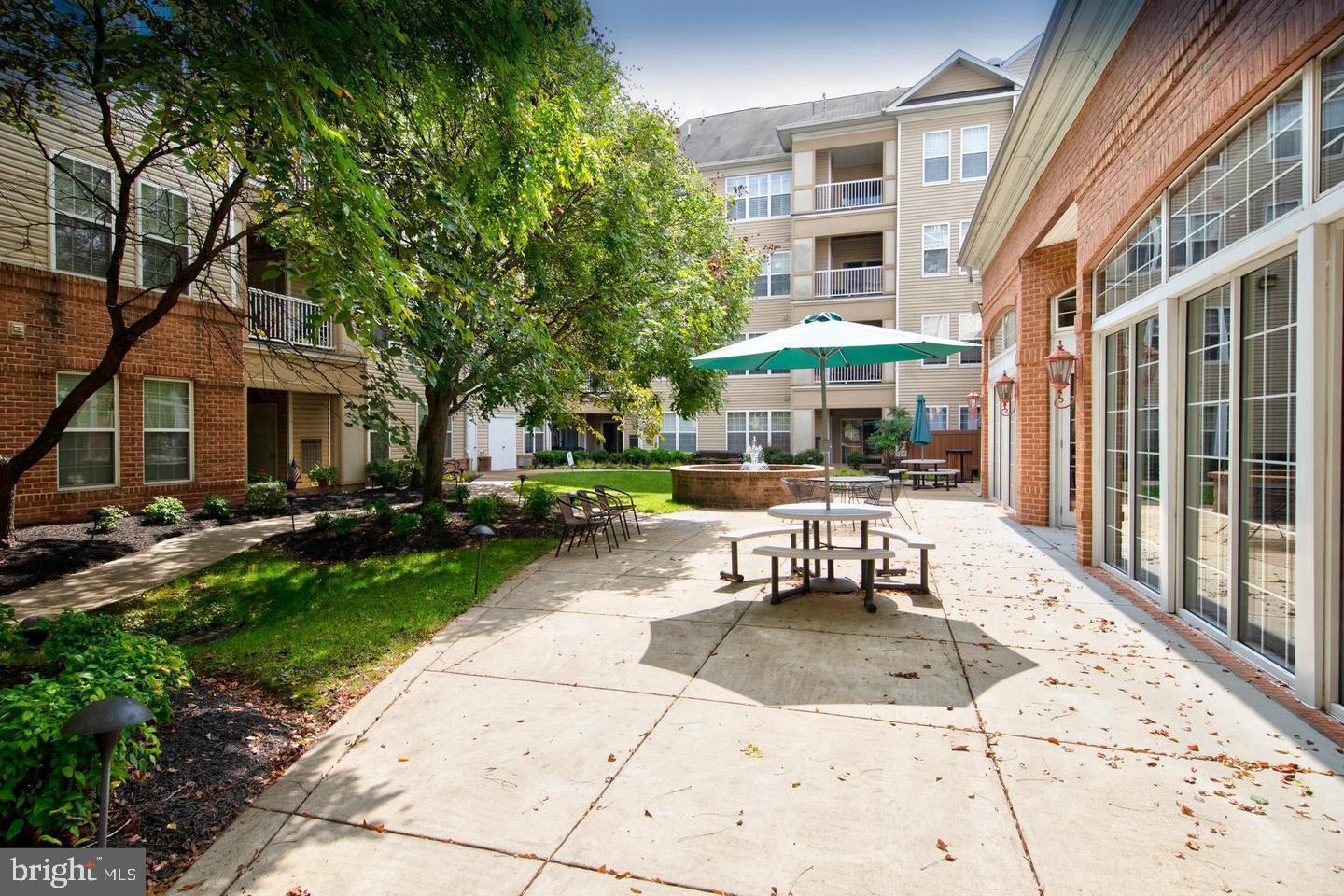 400 Symphony Circle, Unit 74B Cockeysville, MD 21030 - Photo 32 of 36 a patio with a table and chairs under an umbrella