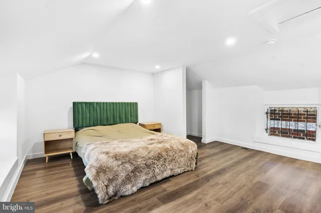 a bedroom with a bed two lamps and wooden floor