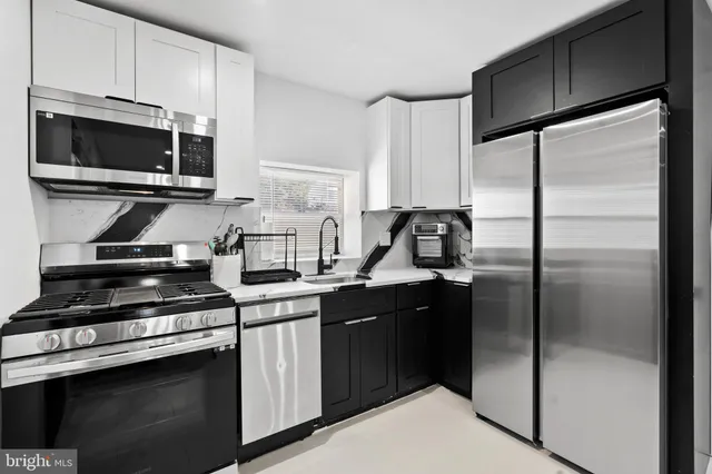 a kitchen with stainless steel appliances a sink a stove a microwave a refrigerator and cabinets