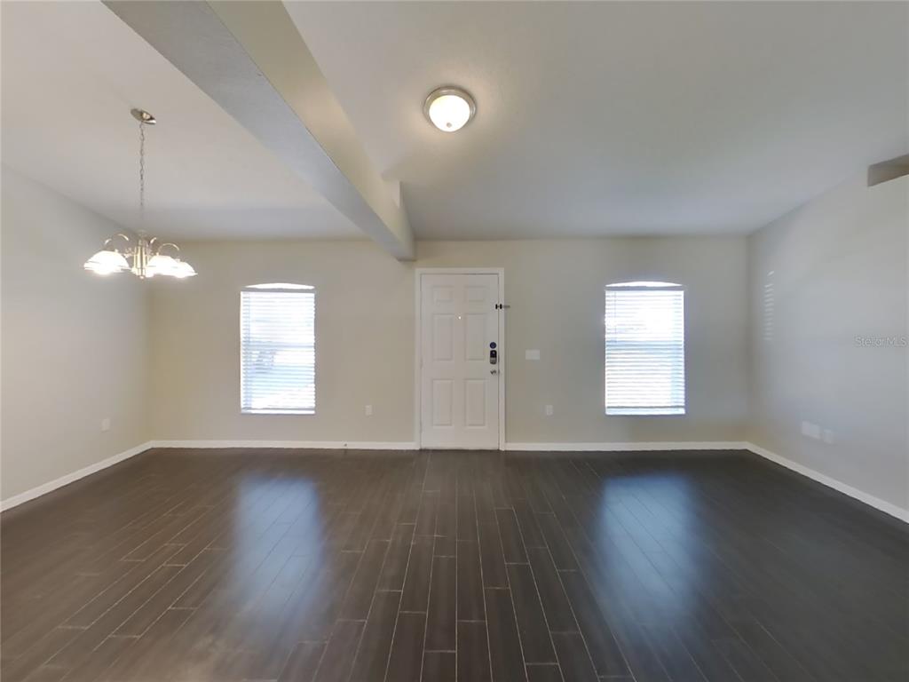 Undisclosed Address Spring Hill, FL 34608 - Photo 6 of 18 a view of an empty room with wooden floor and a window