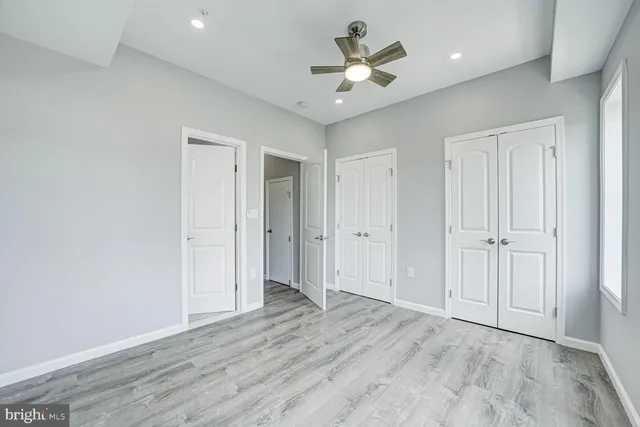 an empty room with wooden floor and ceiling fan