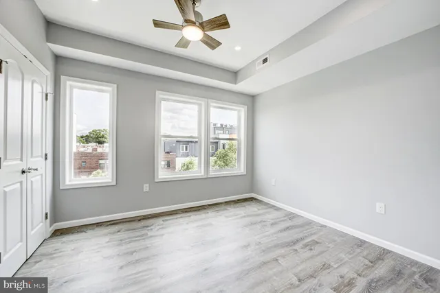 a view of empty room with wooden floor and fan