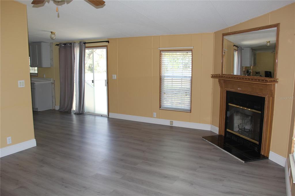 13201 Crowell Road Brooksville, FL 34613 - Photo 9 of 35 an empty room with wooden floor a fireplace and windows