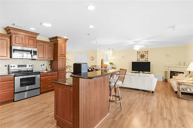 a kitchen with stainless steel appliances a stove top oven a sink dishwasher and a refrigerator with wooden floor