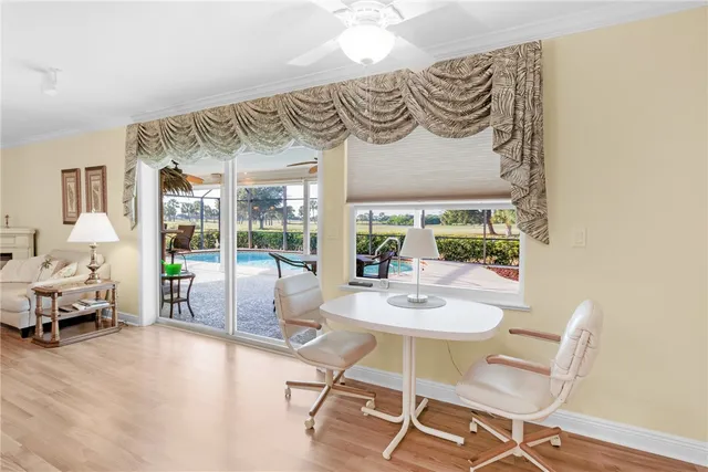 a view of a dining room with furniture one side kitchen view and wooden floor