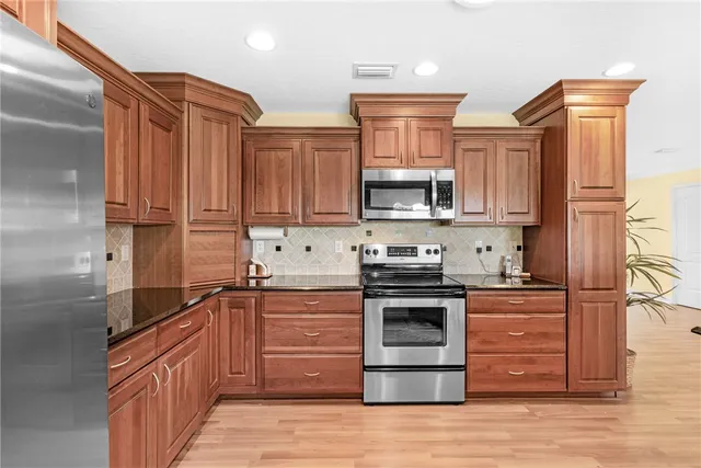 a kitchen with stainless steel appliances granite countertop a stove top oven a sink and dishwasher a oven with wooden floor