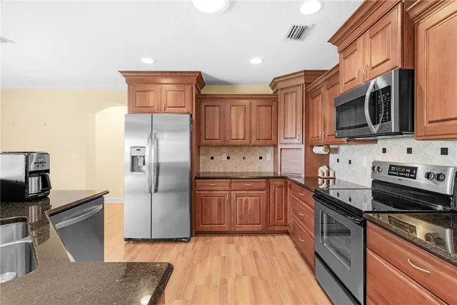 a kitchen with stainless steel appliances granite countertop a refrigerator stove top oven and sink