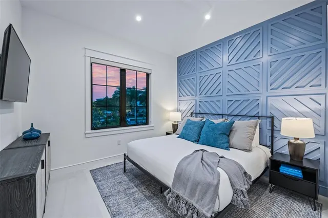 a spacious bedroom with a bed couch and a flat tv screen