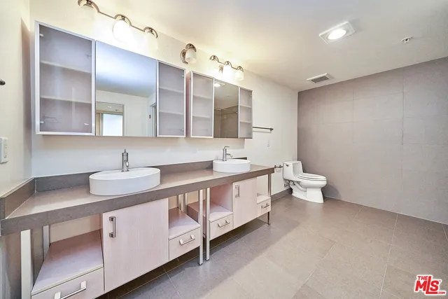 a spacious bathroom with a double vanity sink a mirror and a toilet