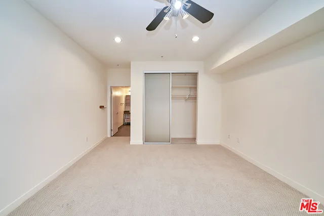 an empty room with chandelier fan and windows