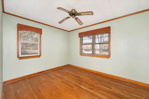 a view of empty room with wooden floor and fan