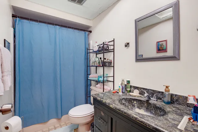 a bathroom with a granite countertop sink mirror vanity and toilet