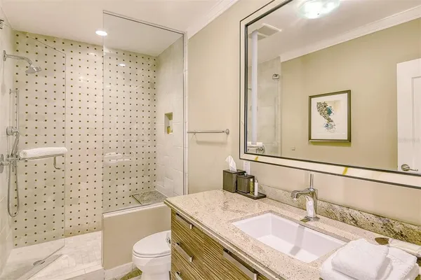 a bathroom with a granite countertop sink a toilet a mirror and shower