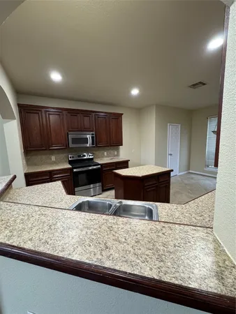a kitchen with stainless steel appliances granite countertop a sink stove and refrigerator