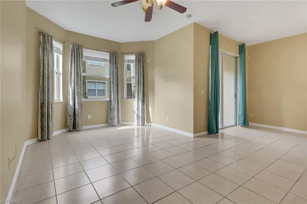 a view of an empty room with window and chandelier fan