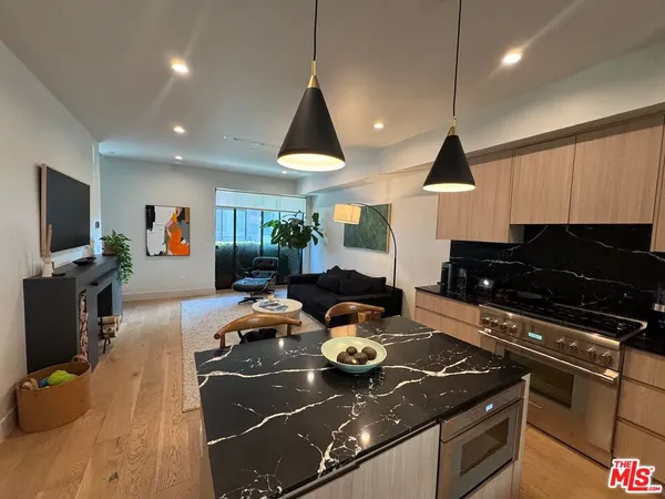 a kitchen with a stove a refrigerator a sink a dining table and chairs with wooden floor